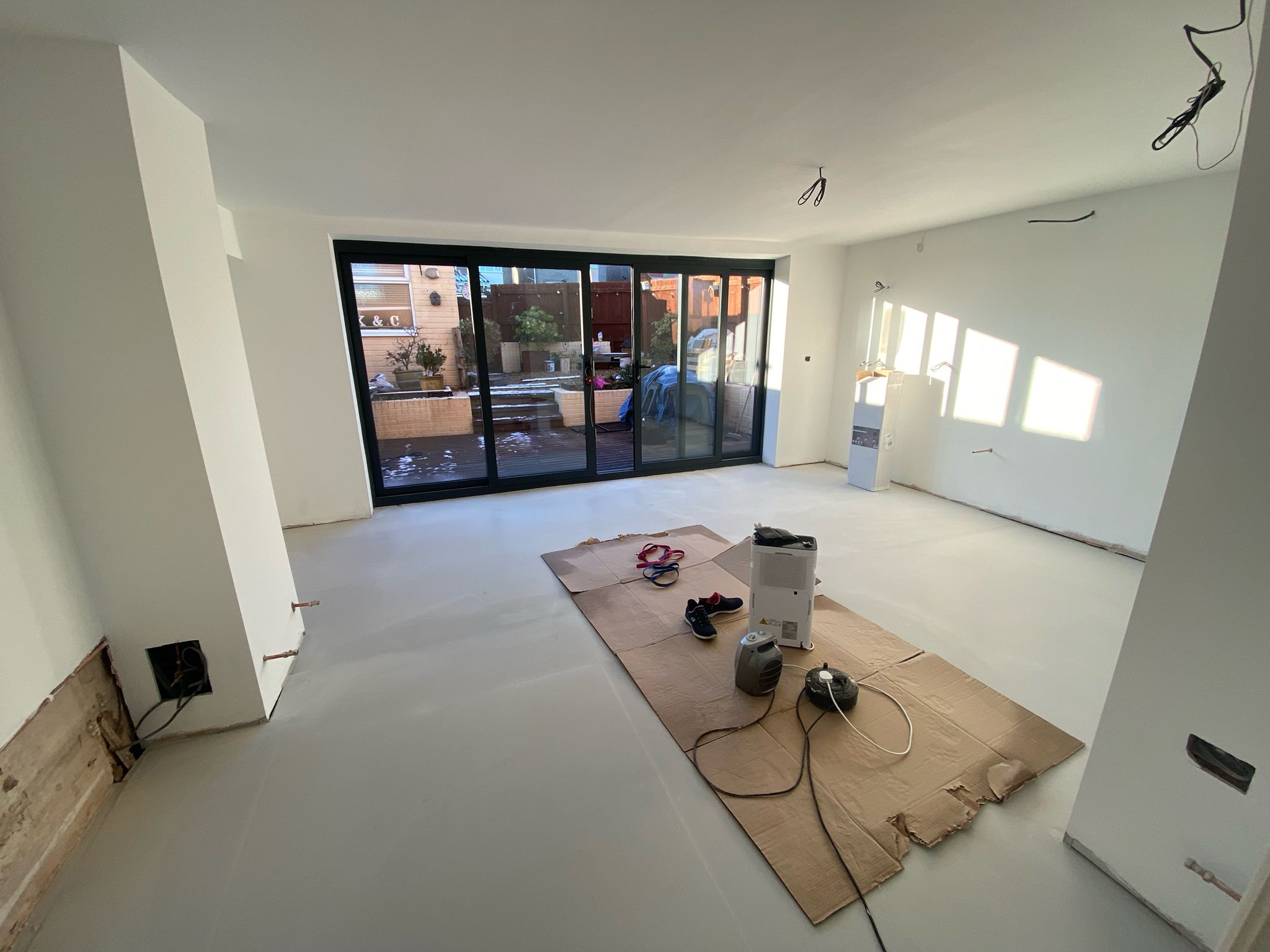 Open-plan kitchen space during renovation with fresh plaster and decoration underway