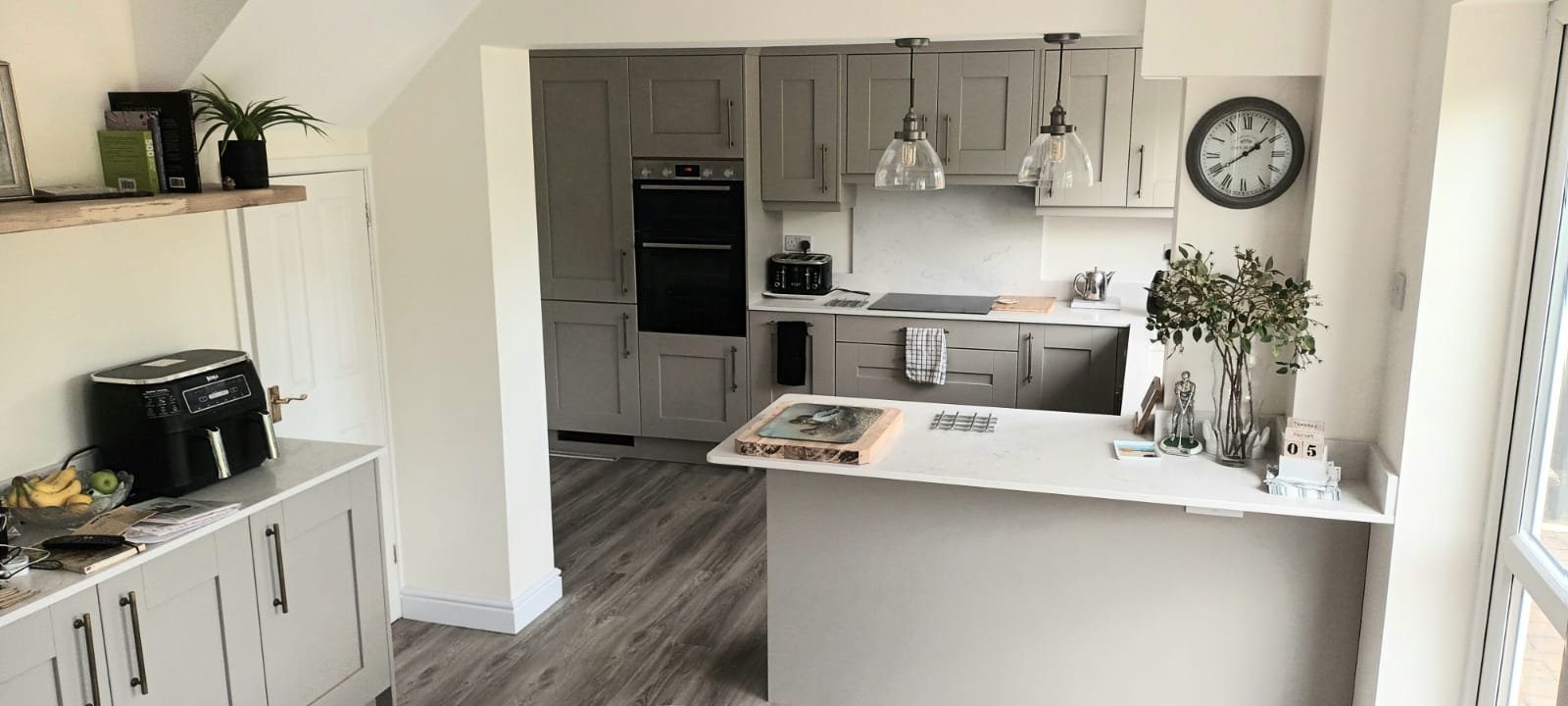 After renovation modern kitchen with grey cabinets, quartz worktops, and breakfast bar