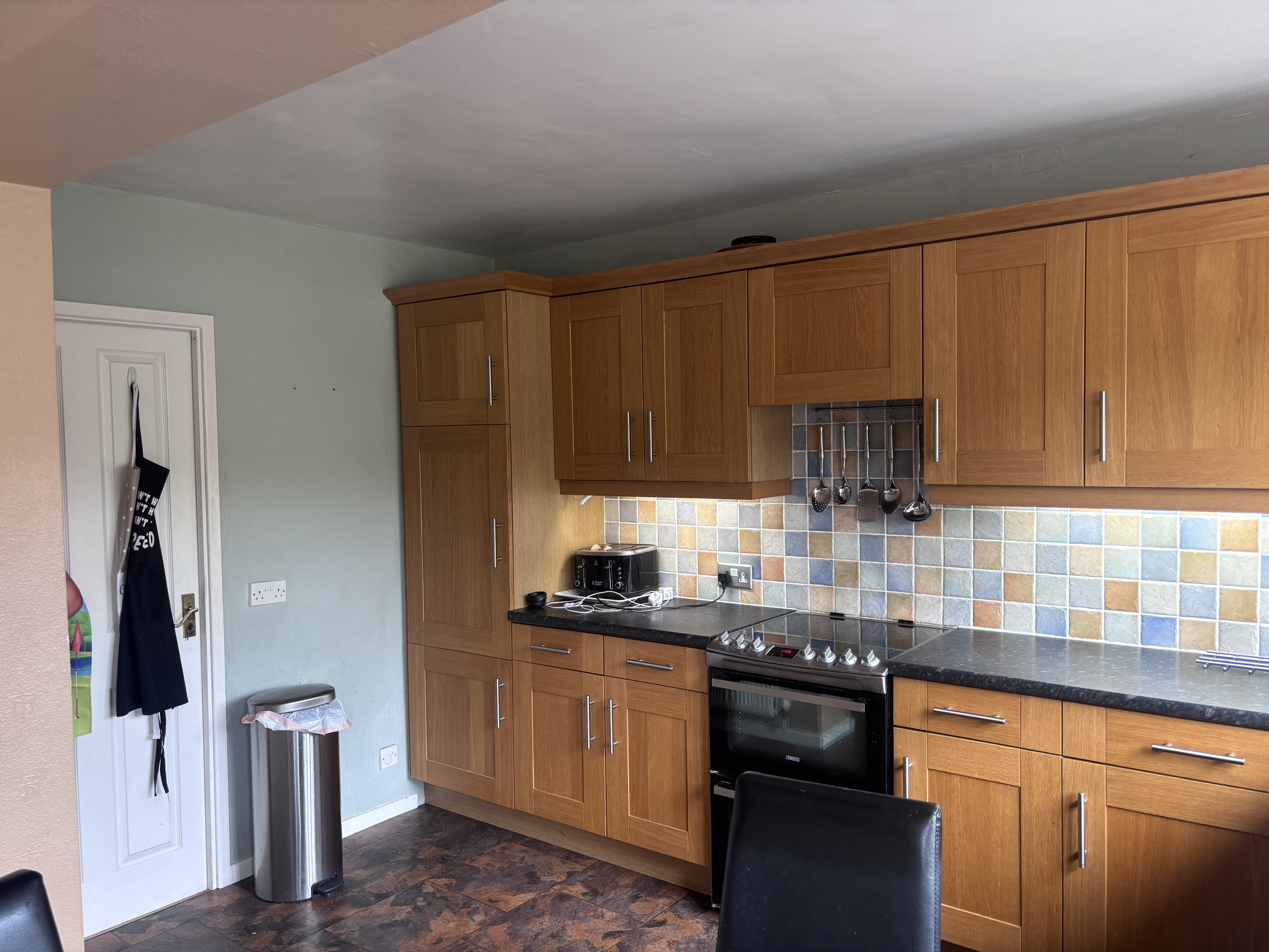 Old kitchen with wooden units and tiled splashback before modern renovation