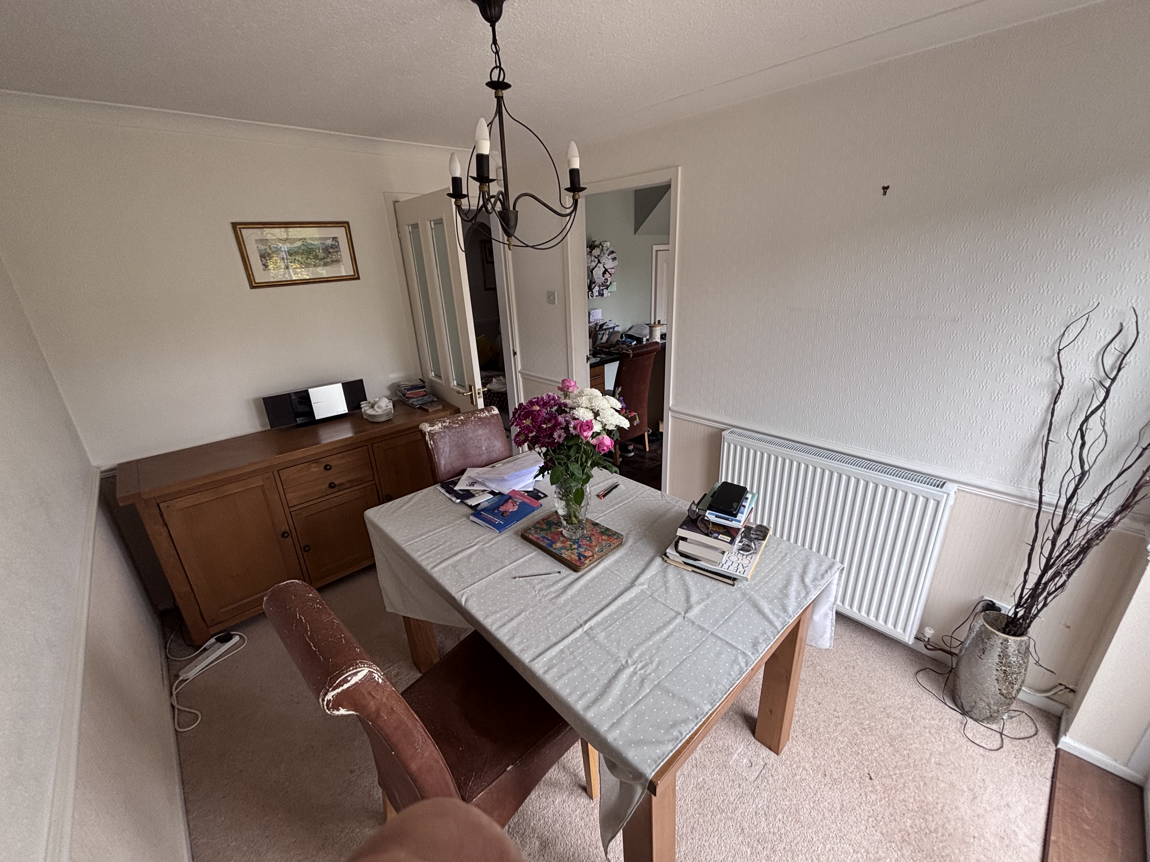 Outdated dining room with wooden furniture, carpet flooring, and wallpaper before renovation